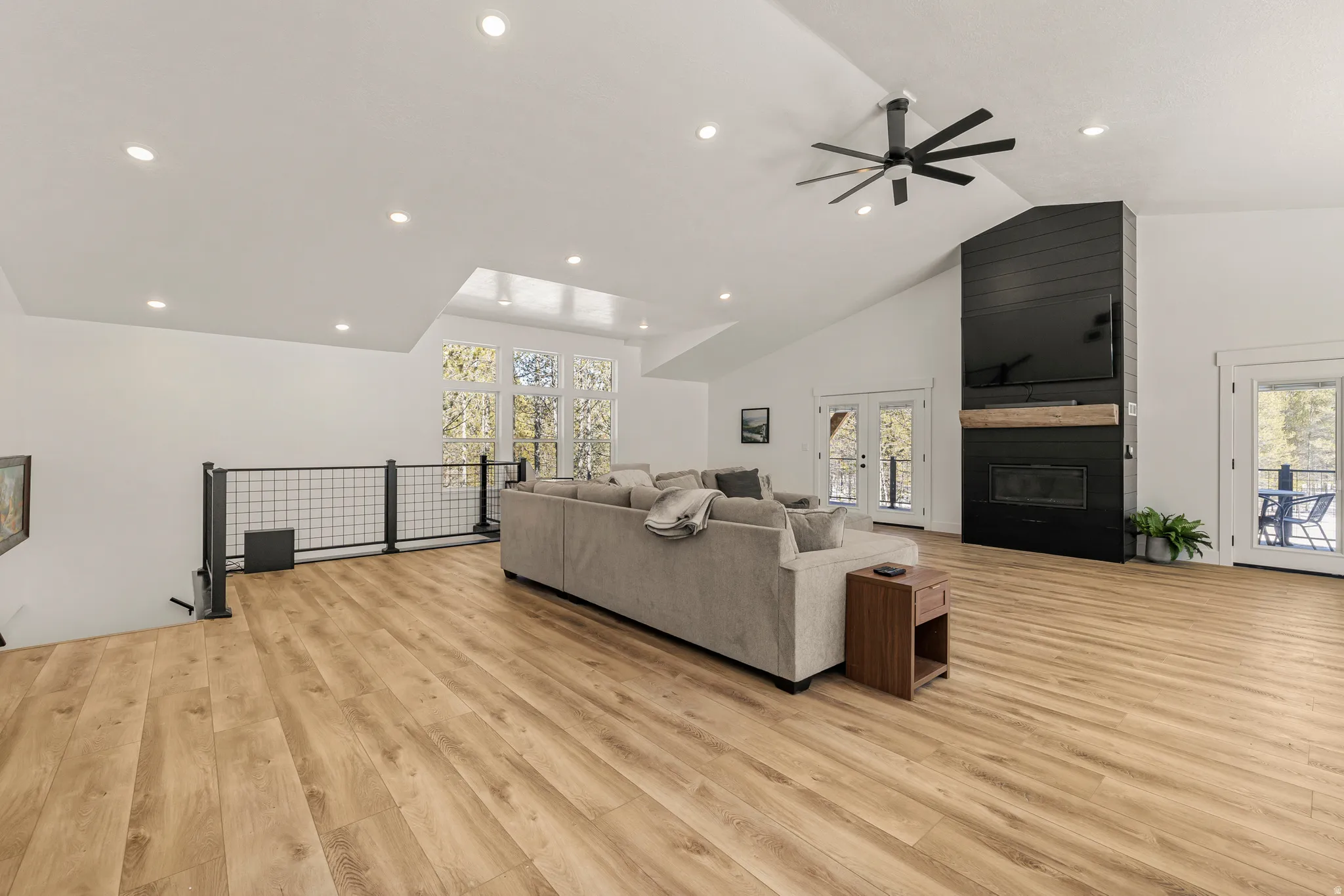 Living area with a high ceiling, light wood-style flooring, ceiling fan, healthy amount of natural light, and recessed lighting