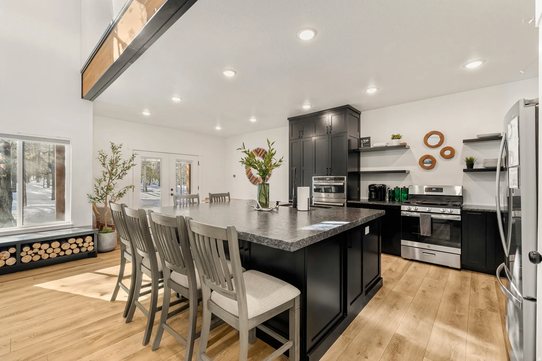 Kitchen featuring dark cabinets, a breakfast bar area, open shelves, french doors, and recessed lighting