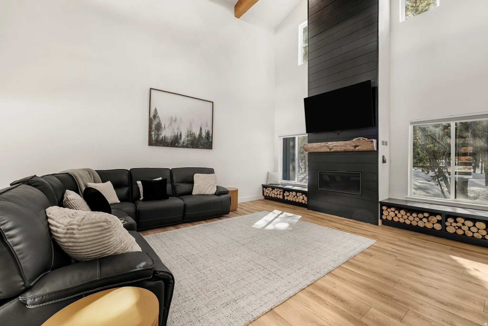 Living room with healthy amount of natural light, a high ceiling, a large fireplace, and wood finished floors