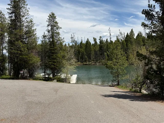 Paved boat launch leading to tranquil waters, surrounded by mature evergreen trees