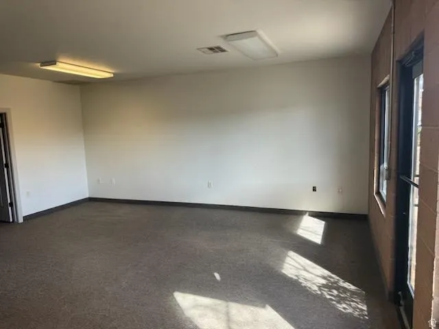 Empty room featuring dark colored carpet and baseboards
