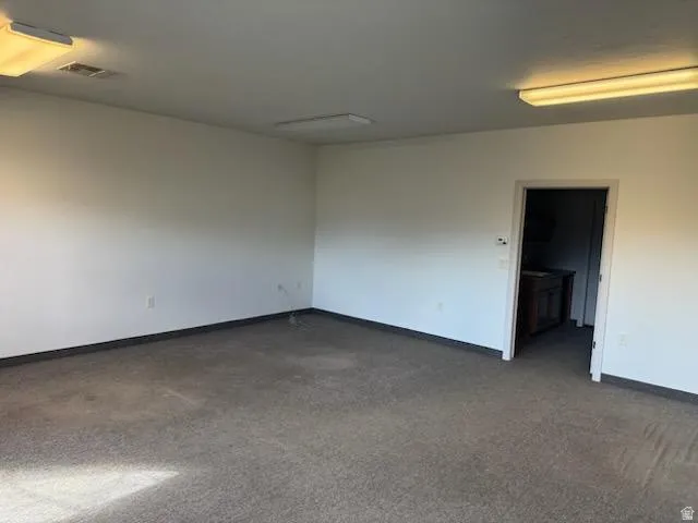 Empty room featuring baseboards and dark carpet