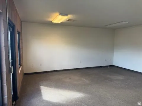 Unfurnished room with baseboards and dark colored carpet