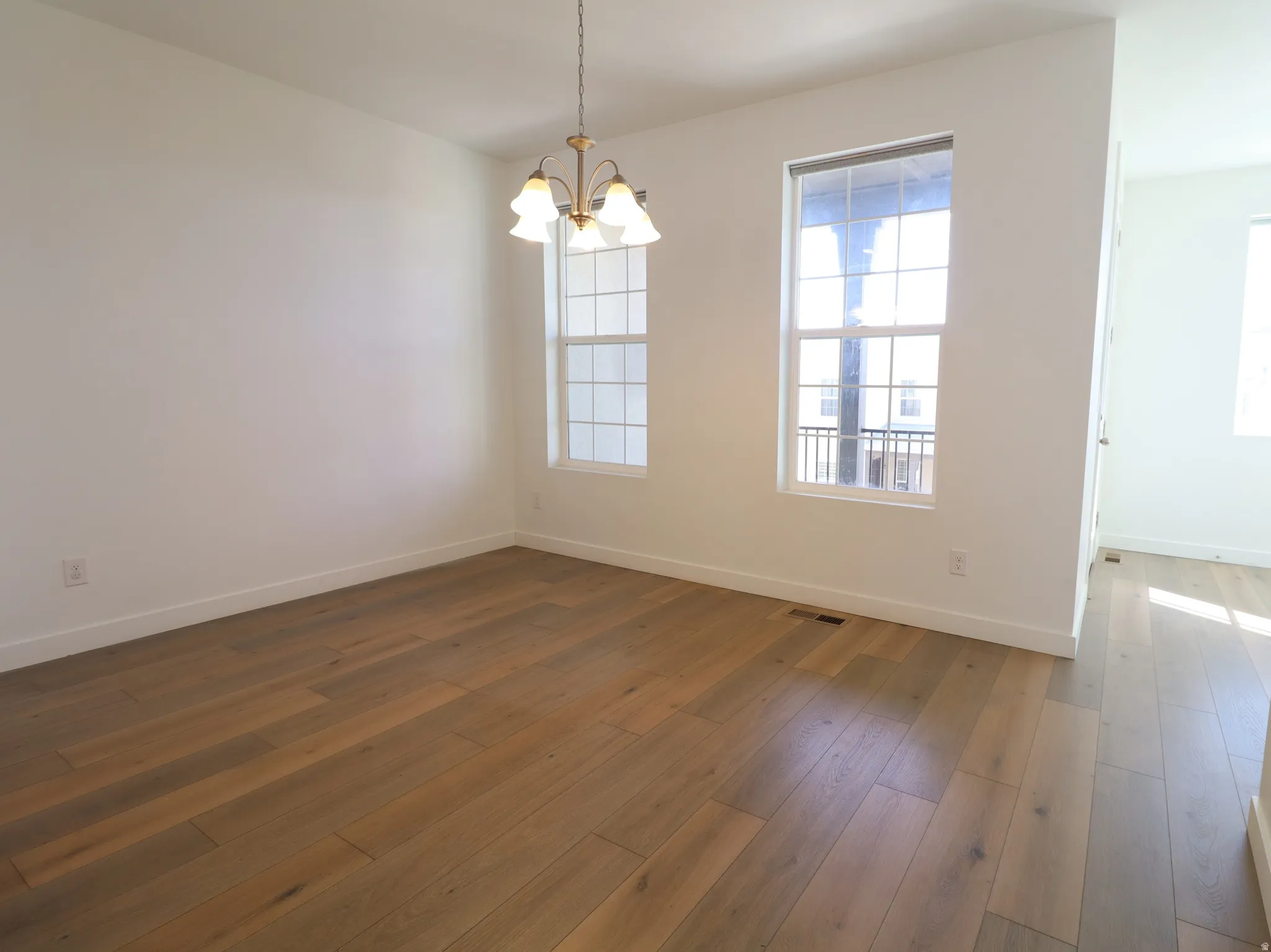 Empty room with hanging lights and dark wood-style flooring