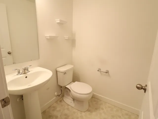 Half bath featuring toilet and baseboards