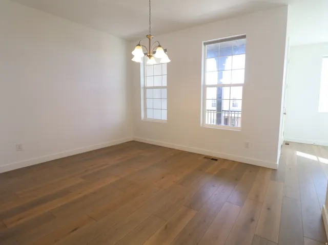 Empty room with hanging lights and dark wood-style flooring