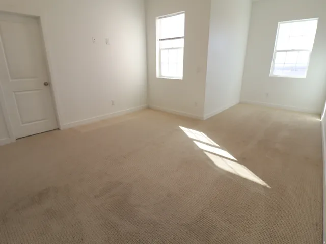 Empty room with light colored carpet and baseboards