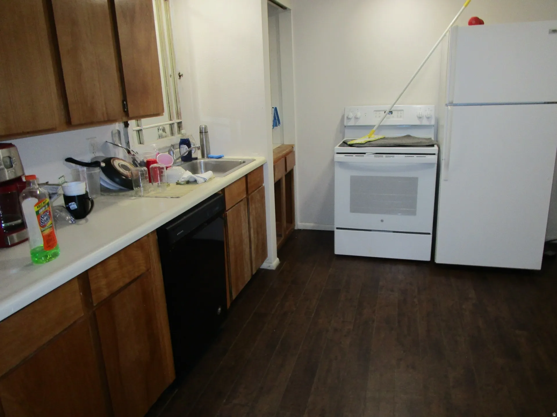 Kitchen featuring white appliances, light countertops, dark wood finished floors, and wood finish cabinets