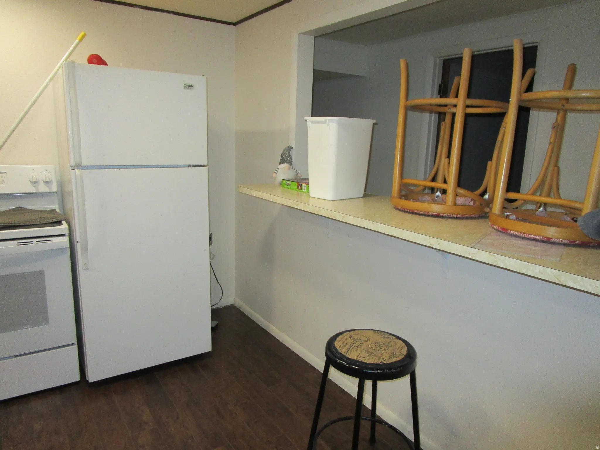 Kitchen with white appliances, dark wood-style floors, and light countertops