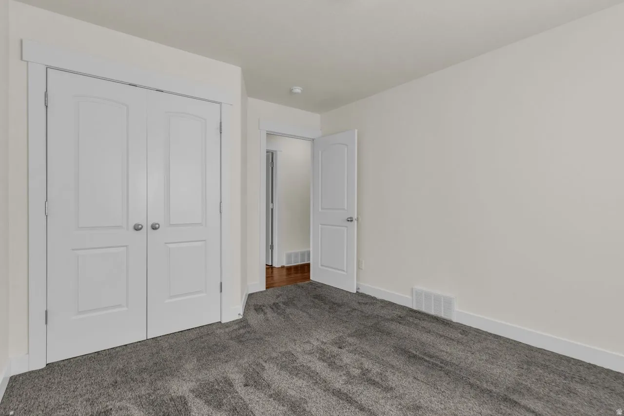 Unfurnished bedroom with dark carpet and a closet