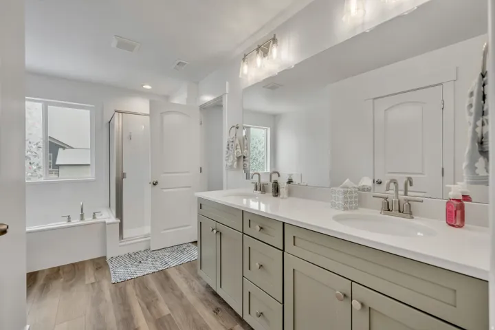 Bathroom featuring double vanity, a stall shower, a bath, light wood-type flooring, and recessed lighting