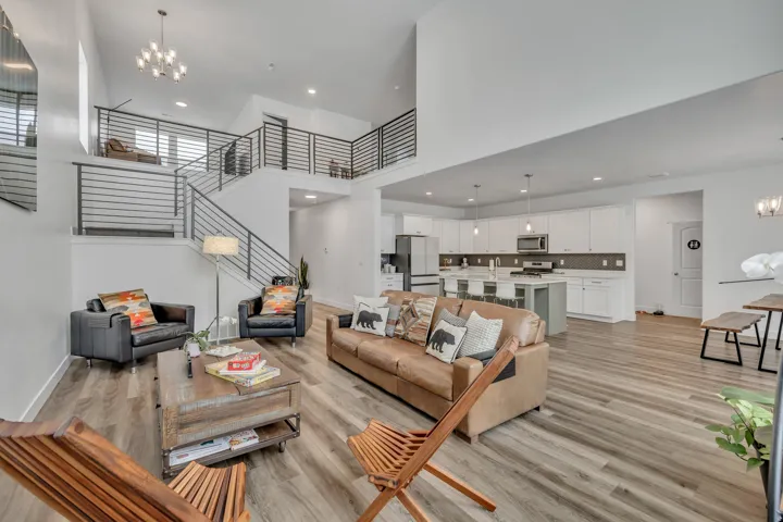 Living area featuring suspended lighting, a high ceiling, and light wood-style flooring