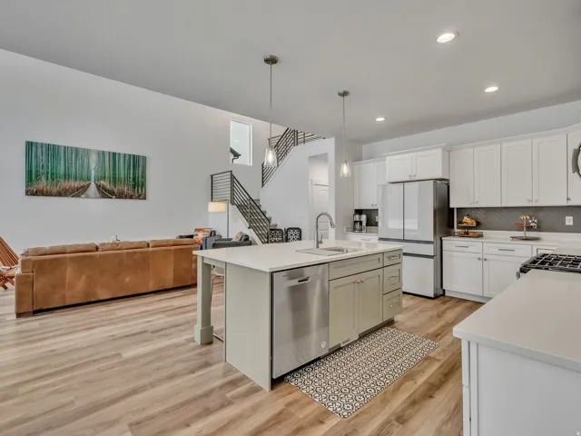 Kitchen featuring open floor plan, light wood-type flooring, freestanding refrigerator, dishwasher, and pendant lighting
