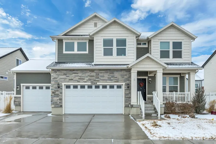 Craftsman-style home with a porch, driveway, stone siding, and an attached garage