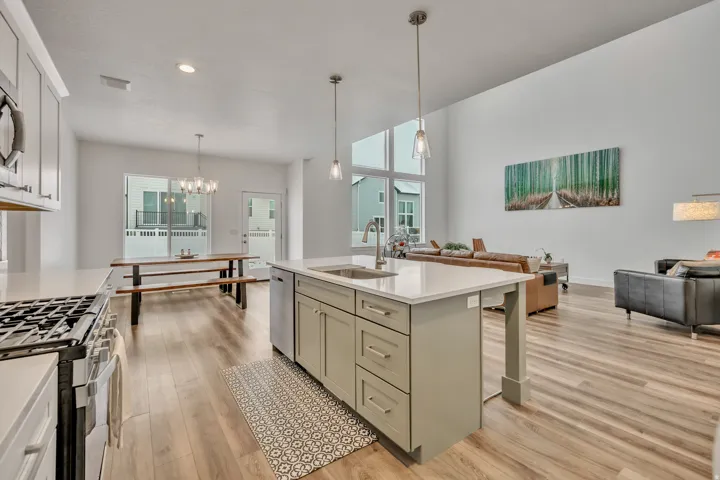 Kitchen featuring open floor plan, light wood-style floors, an island with sink, stainless steel appliances, and suspended lighting