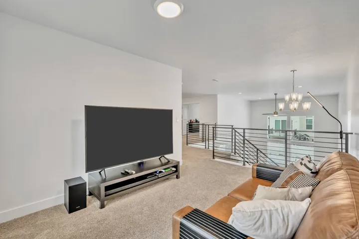 Living area with light carpet and suspended lighting