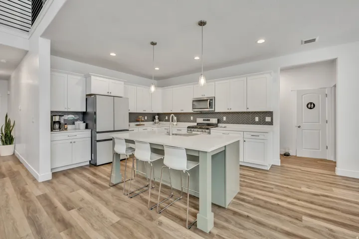 Kitchen featuring a breakfast bar, white cabinets, stainless steel appliances, and a kitchen island with sink