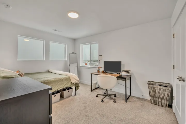 Bedroom featuring light carpet and an office area