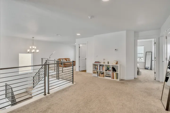 Corridor featuring an upstairs landing, light carpet, and a chandelier