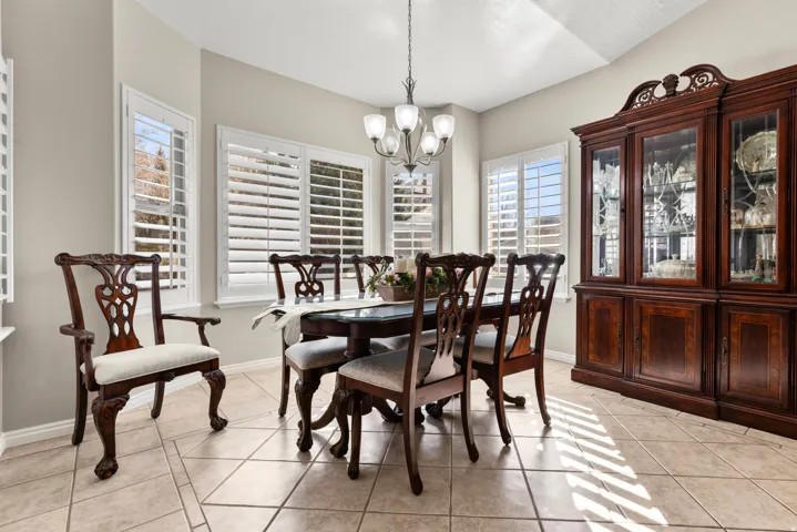 Dining room surronded by windows featuring light tile floors, a hanging light and natural light.