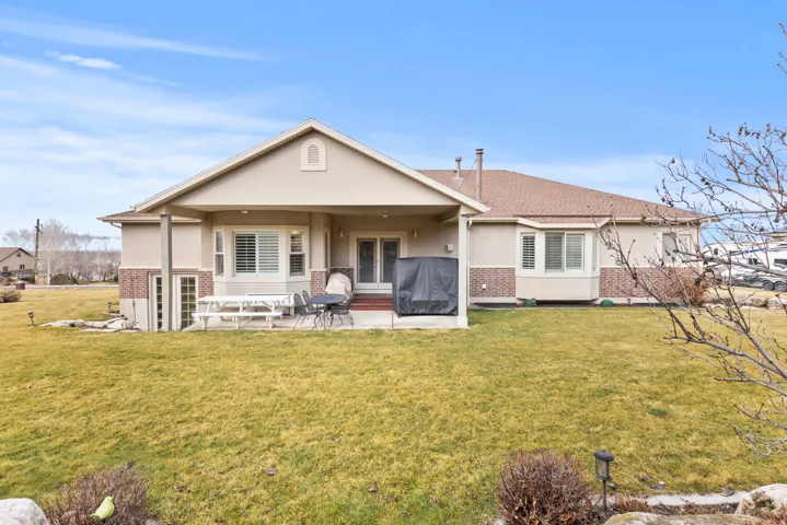 Rear view of house featuring a covered patio area, back lawn
