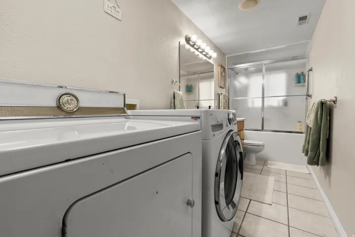 Laundry area/bathroom featuring washer/clothes dryer, light tile floors