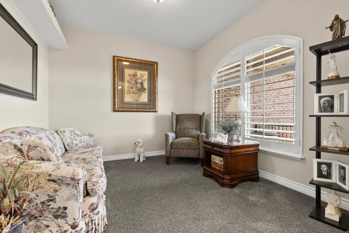 Living area featuring window shutters and dark colored carpet