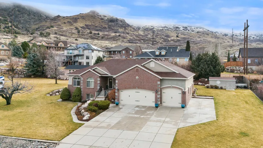 Side view of front of home featuring a front yard, an attached garage, extra parking, and a mountain view