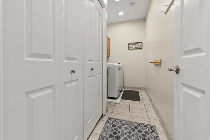 Laundry area featuring light tile floors, washer and clothes dryer, cabinet space, and recessed lighting