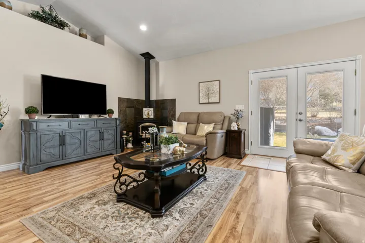 Family room with a wood stove, light wood-style floors, lofted ceiling, french doors, and recessed lighting