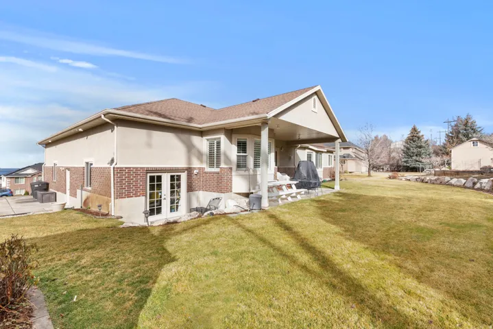 Rear view of property showing back gagage entrance, a covered patio, and lawn
