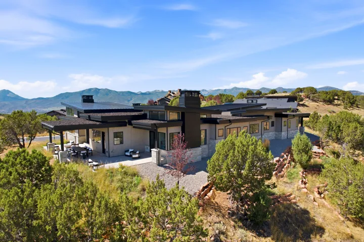 Contemporary architectural design featuring a multi-level structure, stone and horizontal siding exterior, and a large covered patio