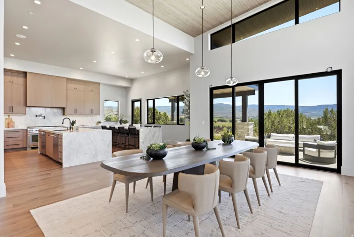 Open-concept living space with a vaulted wood-paneled ceiling, large format sliding glass doors, a kitchen island with stone countertops, and wood-finish flooring throughout