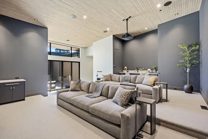 Recessed lighting, wood-finish slatted ceiling, built-in wet bar, tiered seating, and large-format windows