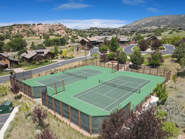 Community tennis courts with a hard court surface, surrounded by natural landscaping and distant mountains