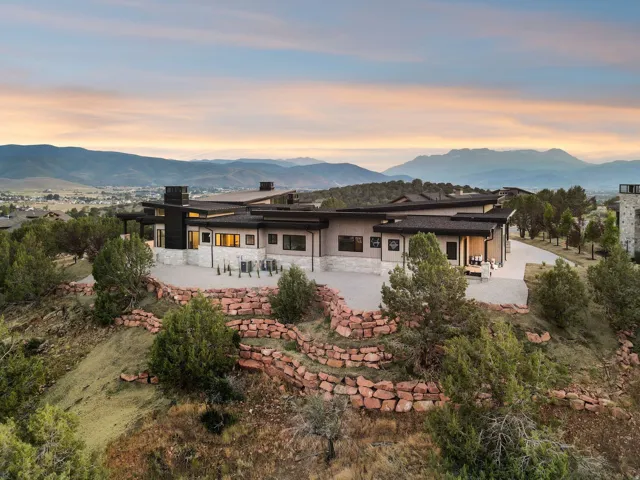 Contemporary dwelling with expansive exterior patio, stone retaining walls, and a multi-level roofline