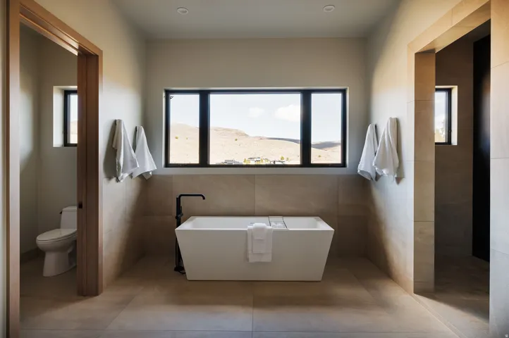 Freestanding soaking tub with a floor-mounted matte black faucet, set against large format tile walls and flooring