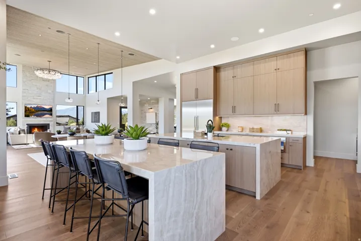 Expansive kitchen island with seating, wood-finish flooring, recessed lighting, and integrated stainless steel appliances