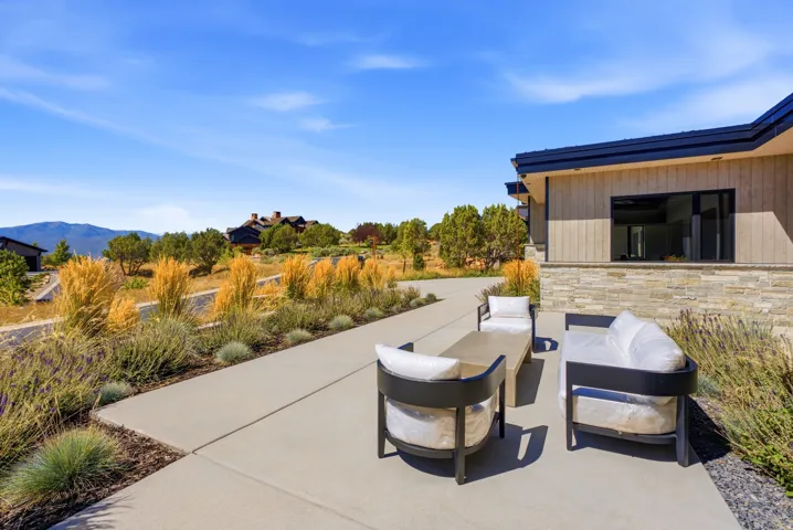 Exterior featuring wood-panel siding, stone veneer, and a concrete patio