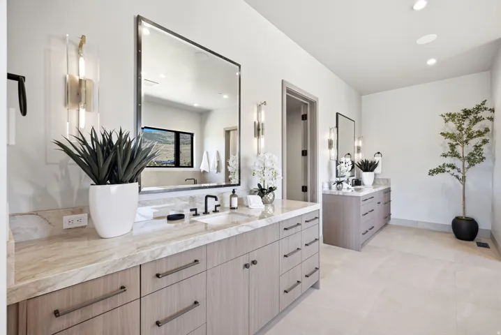 Dual wood-finish vanities with light stone countertops, integrated sinks, and matte black fixtures
