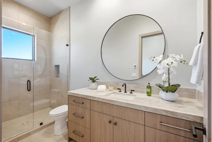 Vanity with integrated sink, wood-finish cabinetry, and stone countertop
