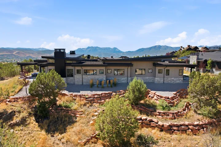 Contemporary exterior with multiple rooflines, stone and stucco facade, an integrated carport, and stacked stone retaining walls