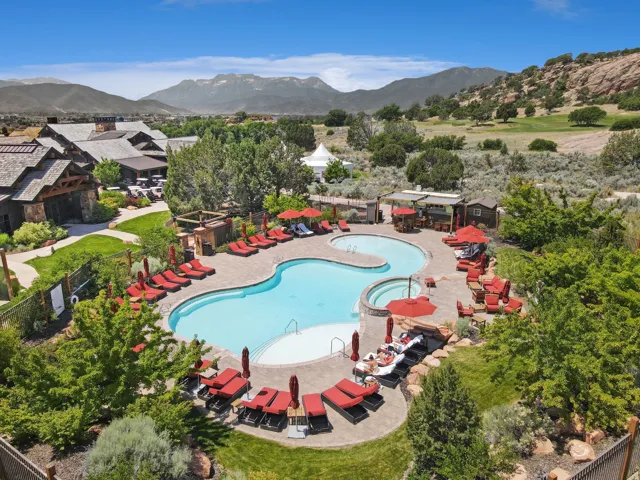 Resort-style pool with integrated spa, expansive paver patio, and surrounding green spaces