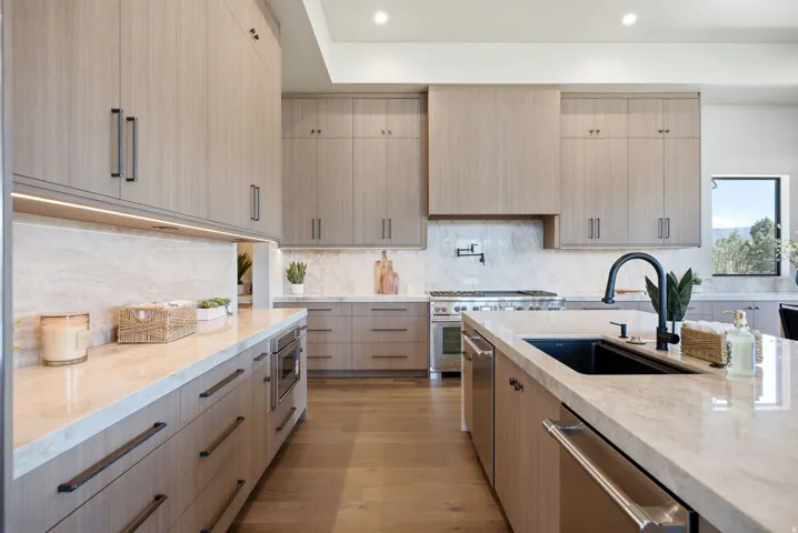 Contemporary kitchen featuring light wood-finish cabinetry, integrated appliances, and light-toned countertops