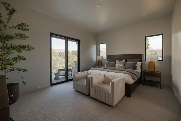 Light gray carpeting, a textured dark wood headboard, black-framed windows, and sliding glass doors opening to an exterior patio
