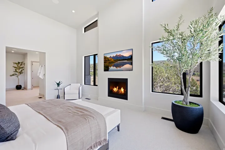 High ceilings, integrated fireplace, wall-mounted television, and large windows with black frames