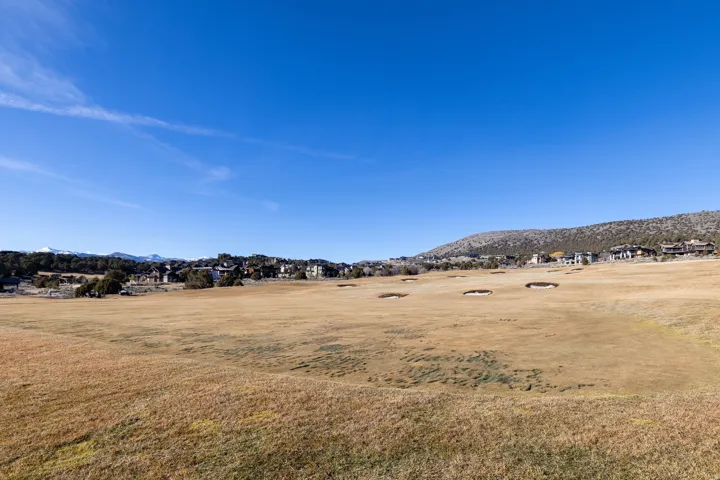 Expansive golf course property with multiple sand traps and mountain backdrop