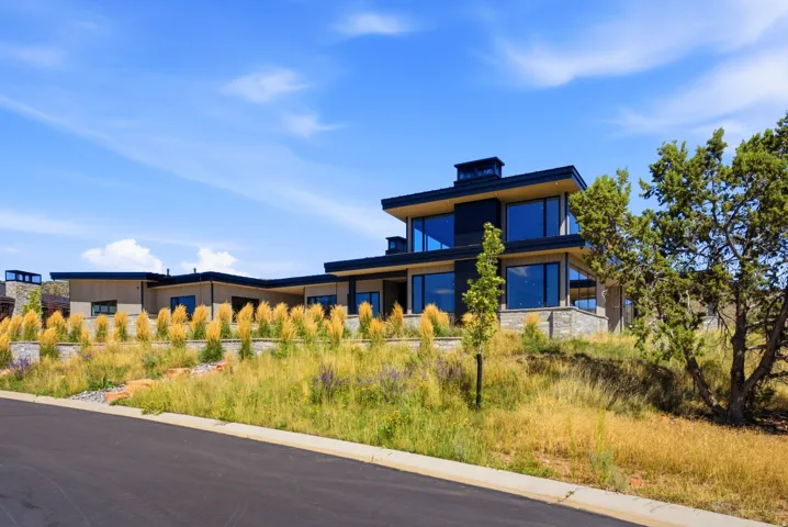Modern architectural style featuring expansive windows, multi-level design, flat roofline, stone veneer accents, and structured landscaping