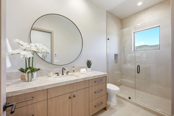 Vanity with a single basin sink, matte black faucet, and light wood-finish cabinetry
