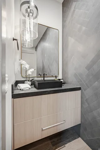 Floating vanity with wood-finish cabinetry, a black vessel sink, and a dark stone countertop